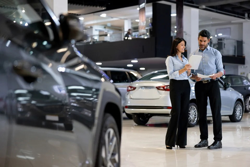 Asesores revisando la documentación entre los autos en exposición